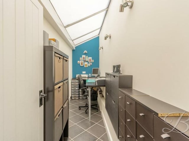 The conservatory extends into this useful office space, with tiled flooring and room for a desk and cabinets.