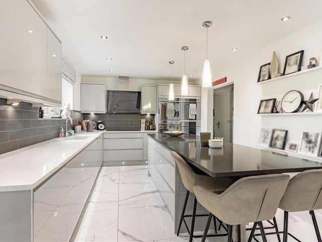 The kitchen from a different angle. Integrated appliances include two ovens, a microwave, two warming drawers, an induction five-ring hob with extractor hood above and a dishwasher.