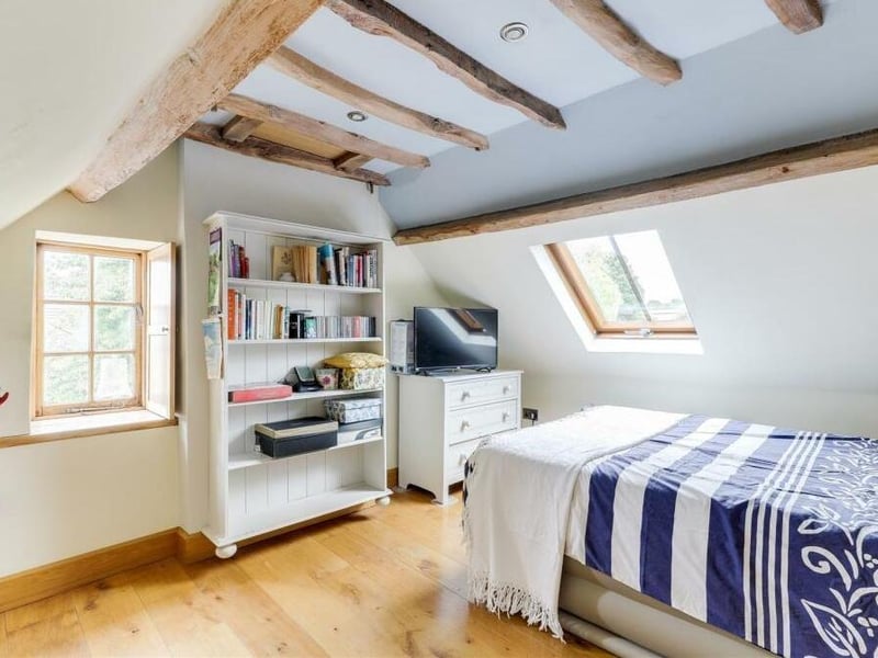 Here is the fourth and last of the double bedrooms, which is on the second floor and faces the side of the cottage. It boasts a vaulted ceiling with exposed oak beams, recessed spotlights, a Velux window and a solid-oak floor.