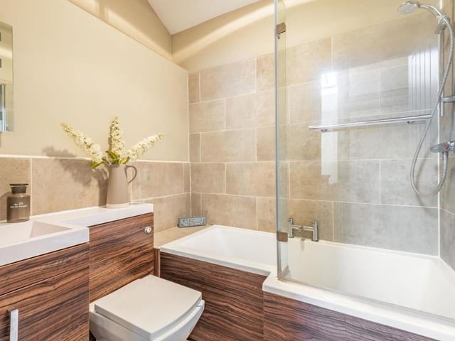 Ensconced among the three bedrooms on the first floor is this family bathroom. It is fitted with a modern three-piece suite, comprising a P-shaped bath and shower over, vanity unit with inset wash hand basin and low-flush WC. The Karndean floor and chrome, heated towel-rail add to its appeal.