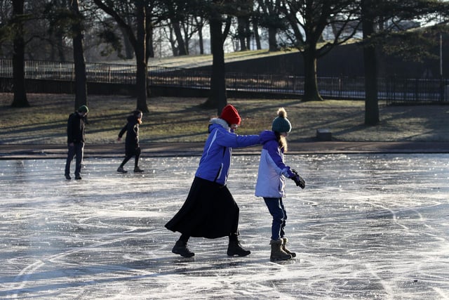 People walk on a frozen pond at Victoria Park in Glasgow.