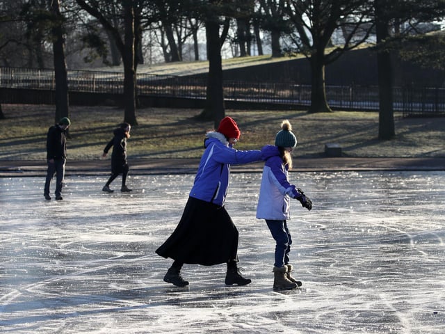 People walk on a frozen pond at Victoria Park in Glasgow.