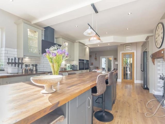 Appliances in the kitchen include an integrated double oven, a dishwasher and induction hob with extractor fan. An oak floor, spotlights and a log burner add to the sleek finish.