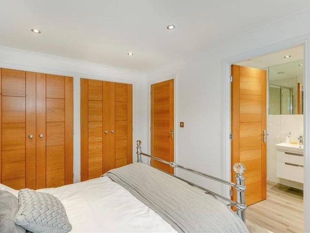 The second bedroom is fitted with stylish wardrobes, complete with hanging rails and shelves. And to the right of the photo is the door to an en suite bathroom.