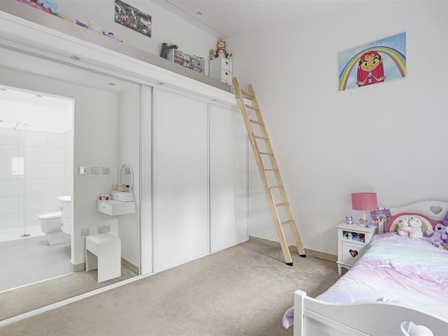 The second bedroom, which also has an en suite, faces the front of the bungalow. It boasts a fitted wardrobe, carpeted flooring, a vertical radiator and recessed spotlights. There is also access to a mezzanine level with a glass balustrade.