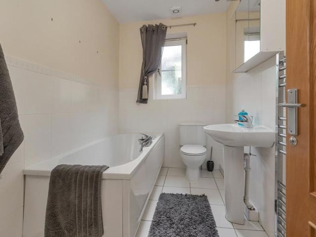 This en suite bathroom features a panelled bath with mixer tap and also a separate shower enclosure. There is also a pedestal wash hand basin, low-flush WC, chrome, heated towel-rail, shaver point and five ceiling spotlights.