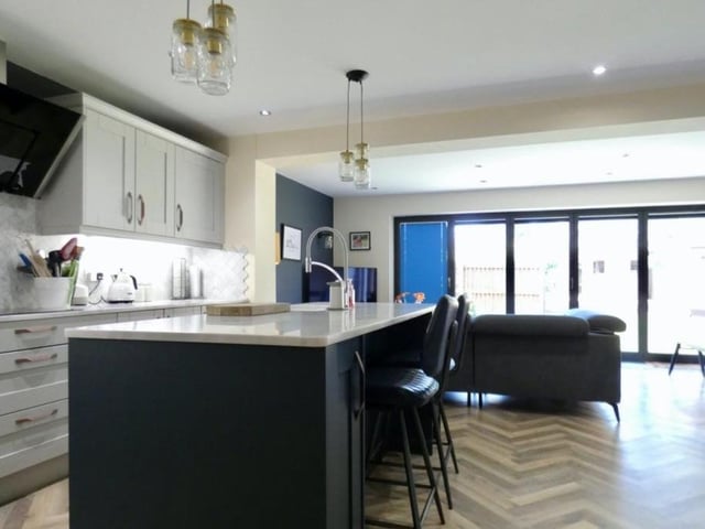 A third view of the kitchen, which is bright and boasts everything you need. The open-plan dining area is in the background.