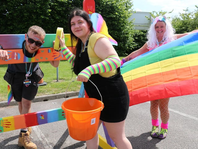 Construction and the built environment student Toni Chapman, centre, prepares to give carpentry and joinery student William Walker a soaking in the stocks, watched by youth worker Ruth Lee holding the rainbow flag.
