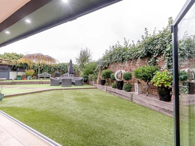 A substantial outdoor entertainment area with ample power and light points, including six LED lights, artificial turf floor, a hot tub area and a heptagon summerhouse.