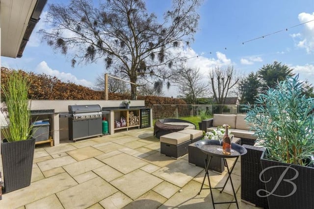 The garden also features this raised patio area, ideal for alfresco entertaining. Not only does it have a seating area but also a glass balustrade, a fitted kitchen with hot and cold water, a Belfast sink and a substantial marble worktop for preparing food. There is space for a barbecue and an outdoor fridge too.