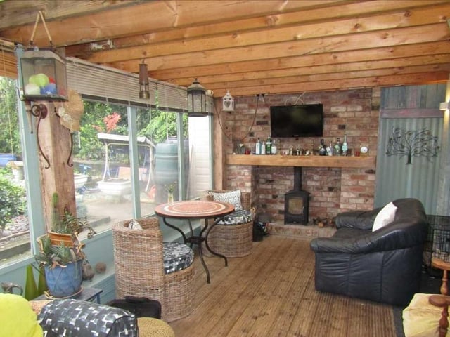 A close-up of one end of the garden room, with its log burner and decked flooring. A lovely place to have a minute!