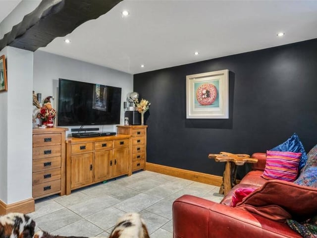 A second view of the sitting room, which is part of the open-plan living space. Feature beams to the ceiling and spotlights add character to the room.