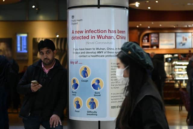 A woman wearing a face mask passes a Public Health England sign, warning arriving passengers that a virus, Coronavirus, has been detected in Wuhan in China, at Terminal 4 of London Heathrow Airport in west London on January 28, 2020. - Chinese President Xi Jinping said Tuesday the country was waging a serious fight against the "demon" coronavirus outbreak and pledged transparency in the government's efforts to contain the disease. (Photo by DANIEL LEAL-OLIVAS/AFP via Getty Images)