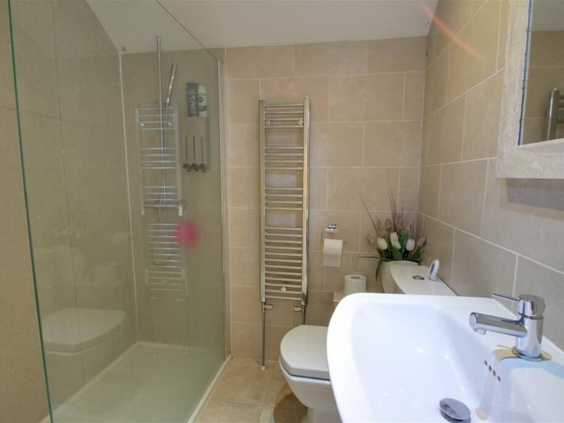 Another of the en suite rooms at the property. This one boasts a walk-in shower, low-flush WC and pedestal wash hand basin. It is fully tiled and comes with a heated towel-rail.