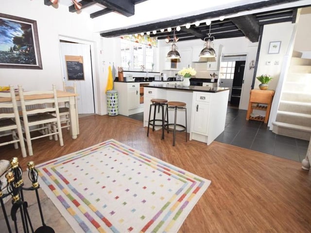 A photo that underlines how spacious the dining kitchen is and how much of a farmhouse feel it has. The on-trend central island incorporates a functional breakfast bar, with units and drawers for extra storage. The stairs on the right lead directly to the first floor of the cottage.