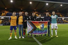 Players from Mansfield Town Football Club stand with Proud Stags founders at One Call Stadium, Mansfield.