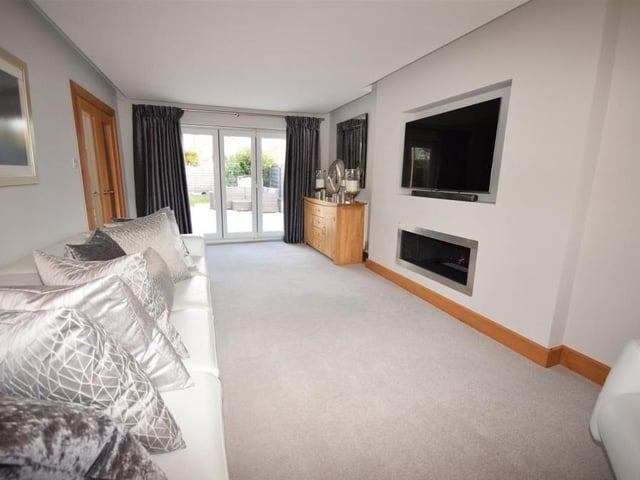 A view of the sitting room from a different angle, showing the doors that lead to the back garden. One of its assets is a floating ceiling with recessed lighting.