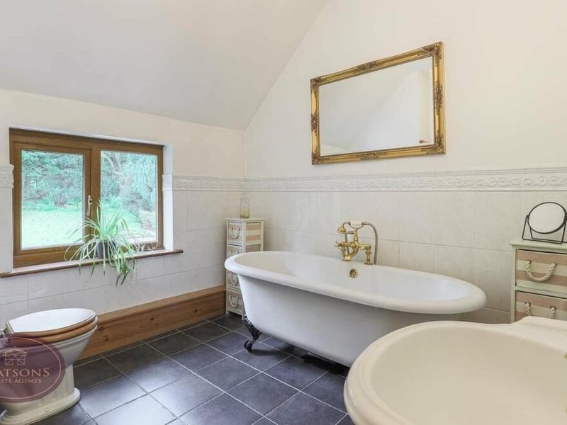 The delightful family bathroom is in keeping with the rest of the historic house, especially the free-standing roll-top bath with mixer shower. There is also a pedestal sink unit, WC, heated towel-rail and tiled flooring.