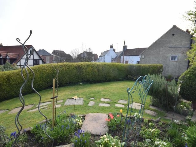 The cottage's pretty garden at the front is adorned with shrubs and flowers. There is also a meandering path that leads to the front door
