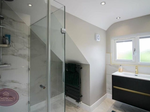 Here is the en suite shower room that is attached to the main bedroom. A three-piece suite in white comprises a WC, vanity sink unit and shower cubicle. There is also a heated towel-rail, ceiling spotlights and an extractor fan.