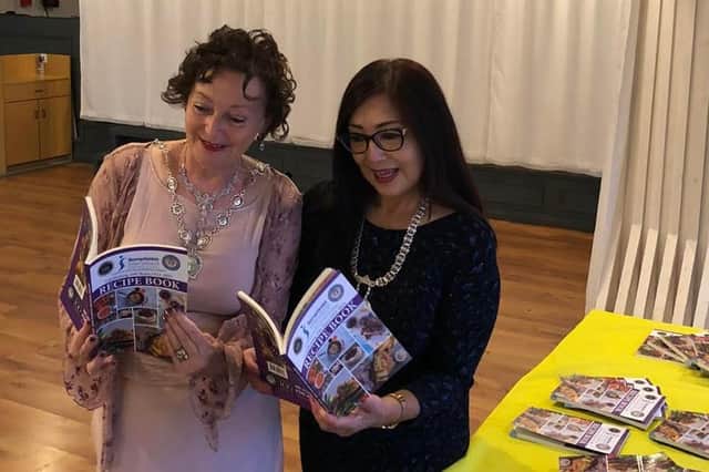 VIP guest Kam Britland (right), a regional president of Soroptimist International, and Julie Howe-Shilton, president of the Mansfield branch, browse through the new recipe book at the celebration dinner.