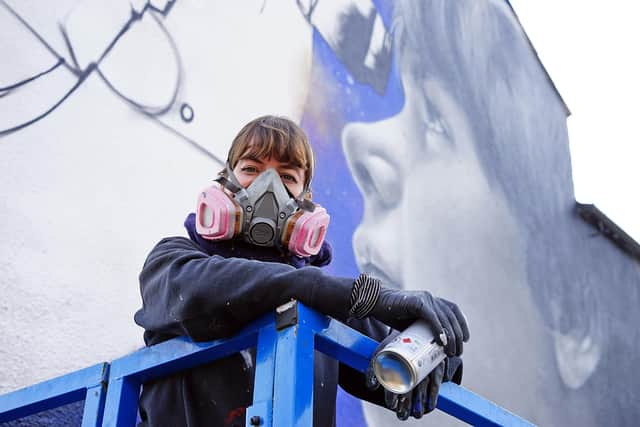 Zabou - a French artist is seen painting a mural on a building at Sutton.