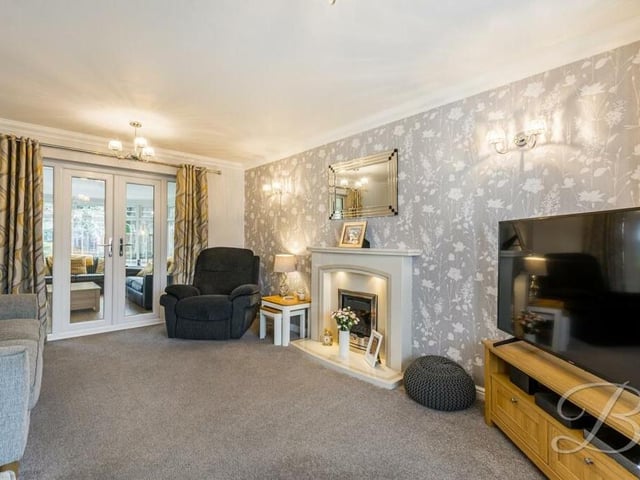 The living room creates a warm and cosy atmosphere, thanks largely to its delightful feature fireplace and fitted carpets.