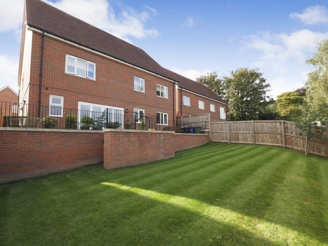 A quick look outside shows the view from the back of the Wildflower Rise property. A sizeable patio has steps that lead down to a well-maintained and enclosed lawn.