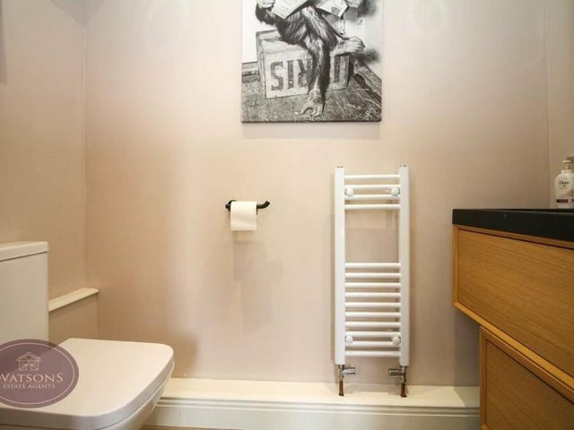 The downstairs bedroom has access to this en suite toilet. The room consists of a two-piece suite in white, with a WC, vanity sink unit, heated towel-rail and ceiling spotlights.