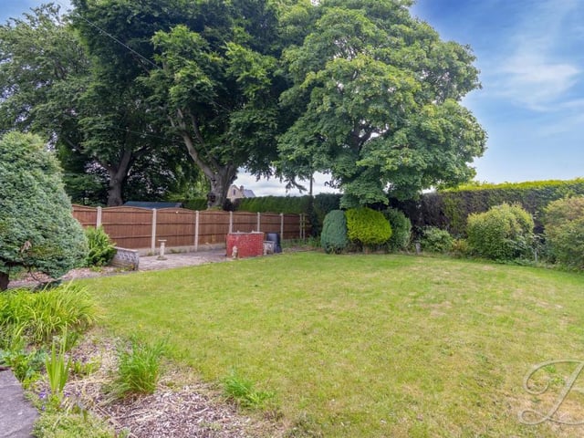 The spacious garden at the side of the bungalow features some terrific surrounding mature shrubs and trees.