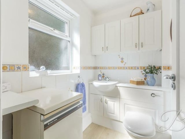 The ground floor is completed by this toilet, which comprises a low-flush WC, vanity hand wash basin and storage cupboards.