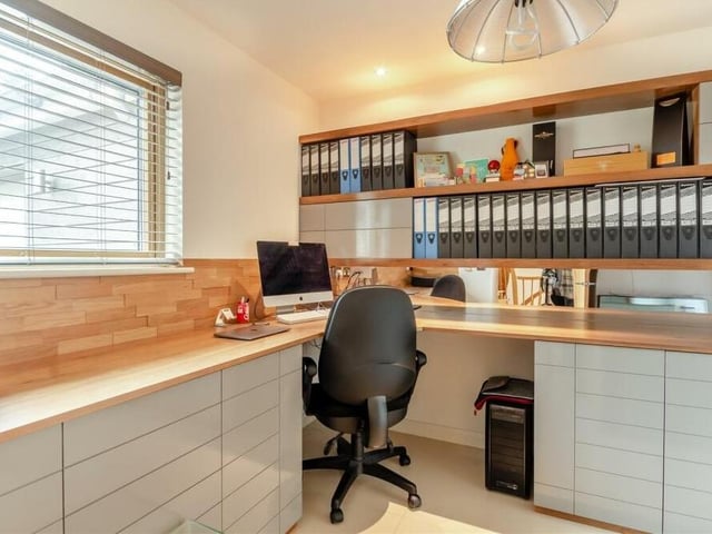 The ground floor of the Coxmoor Road property also houses this home office or study, which is fitted with solid walnut furniture and oak panelling. There is a large L-shaped desk and three rows of shelving above, plus extensive, built-in drawers and a storage cupboard.