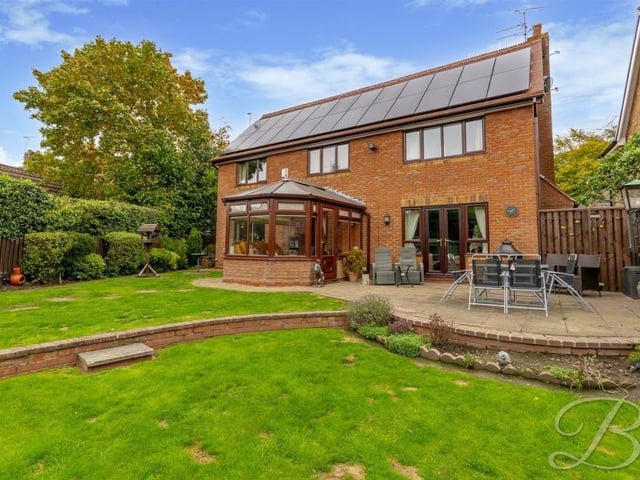 Stepping outside now, and this is the view from the back garden, with its lawn and patio area. The conservatory juts out, while the French doors lead from the lounge.