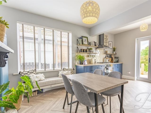With the dining area in the foreground, this photo shows how bright and spacious the kitchen is. As well as the French doors, there is a window to the side of the bungalow. A feature fireplace adds to the room's appeal.