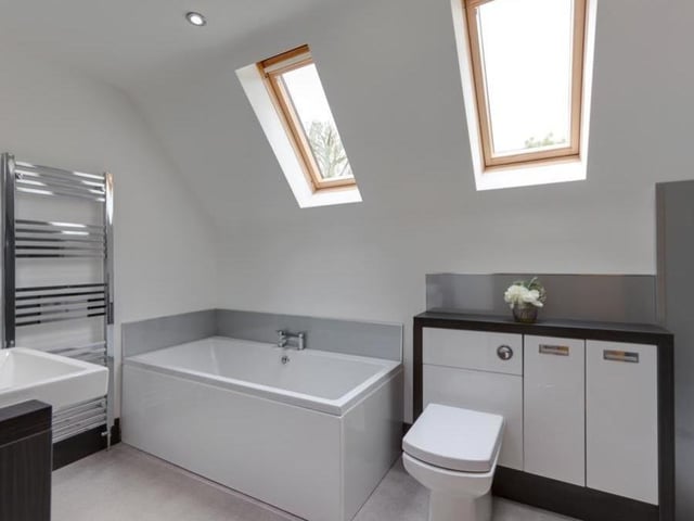 The en suite to the master bedroom is a fabulous white suite, comprising a panelled bath, walk-in shower enclosure, vanity unit with wash hand basin, open shelving and cupboards, and also a low-level WC with fitted storage. Two Velux roof windows, recessed lighting and a chrome, heated towel-rail add to its appeal.