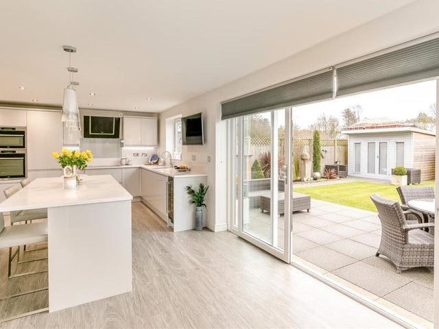 This photo shows how the large sliding doors of the kitchen open on to the patio. It also points out the central island or breakfast bar, which has space underneath for stools or chairs.