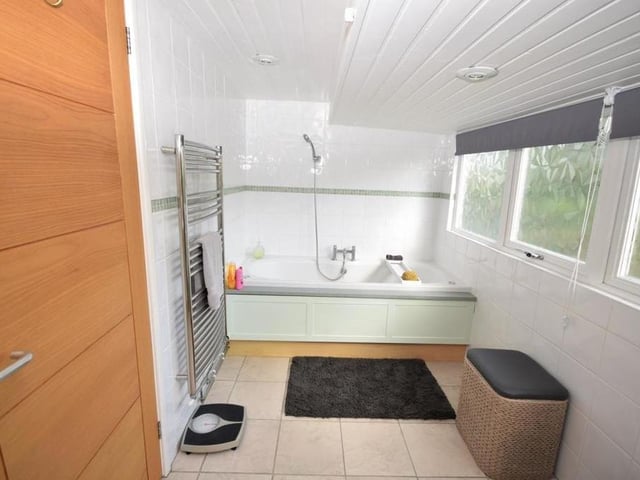 The family bathroom is fitted with a panelled jacuzzi bath that also has a shower fitting. It is decorated with tiled walls and a tiled floor.