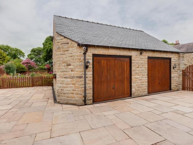 The property's double garage, surrounded by off-street parking space. It boasts two electric, up-and-over doors, light and power, while a timber staircase inside rises to a store.