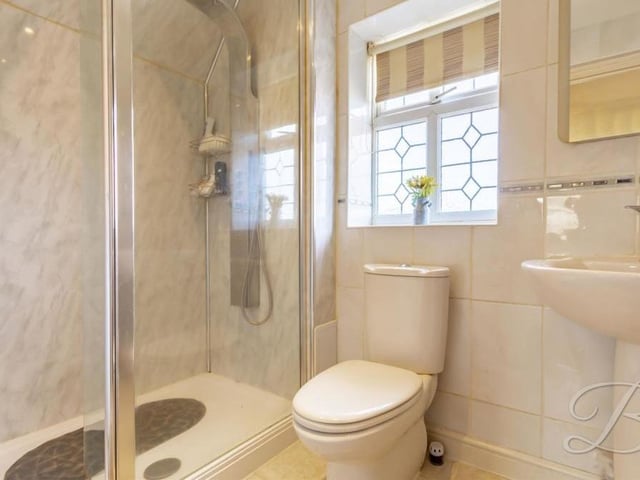 The two main bedrooms at the Sutton house boast their own en suite bathrooms. Here is one of them, comprising a walk-in shower cubicle with waterfall shower, hand wash basin, low-flush WC and full-height tiling.
