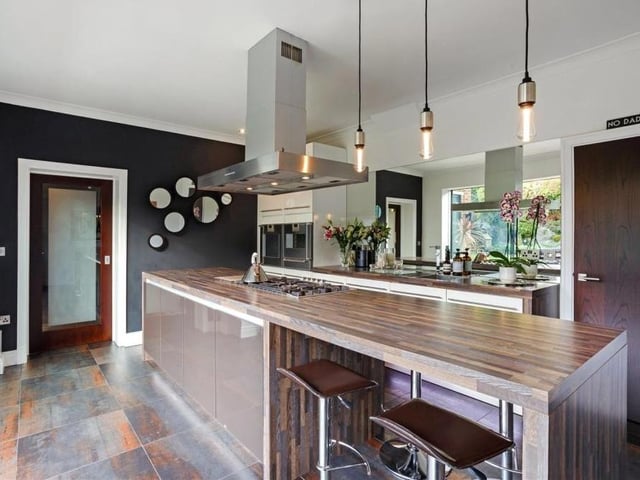 The sleek kitchen from a different angle. It has a built-in dishwasher and inset sink with waste disposal and drainer. Modern, attractive tiling and further underfloor heating add to the kudos of the room.