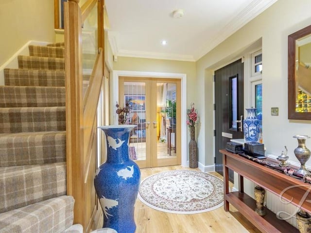 The spacious hallway includes a carpeted staircase, with glass balustrade, leading to the first floor.