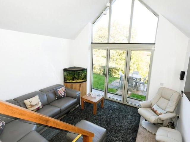 This photo shows how the smart second living room sits snugly behind the feature window, on a slightly lower level to the kitchen. The doors lead to the garden.