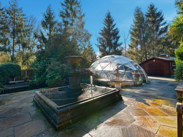 Set within a generous stone-paved terrace sits a distinctive geodesic greenhouse dome, offering a practical space for year-round growing.