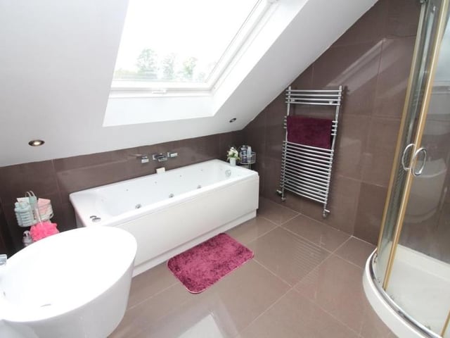 The primary bedroom has access to this luxurious en suite bathroom, which is fitted with a white four-piece suite. It comprises a whirlpool bath, corner shower cubicle with mains-fed rainfall-effect shower, floating sink, WC, chrome heated towel-rail, skylight window, ceiling spotlights and extractor fan.