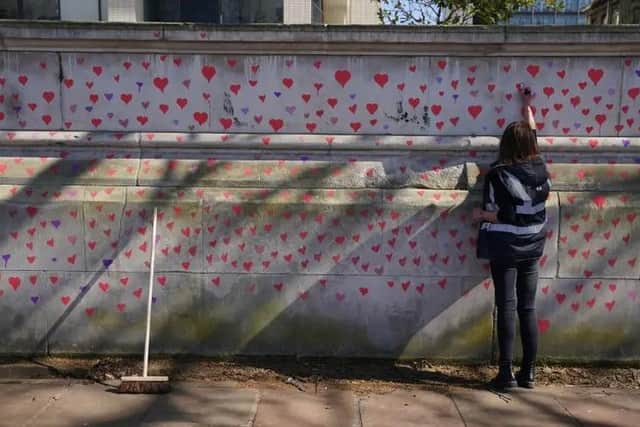 Another heart is added to a wall remembering victims of Covid.