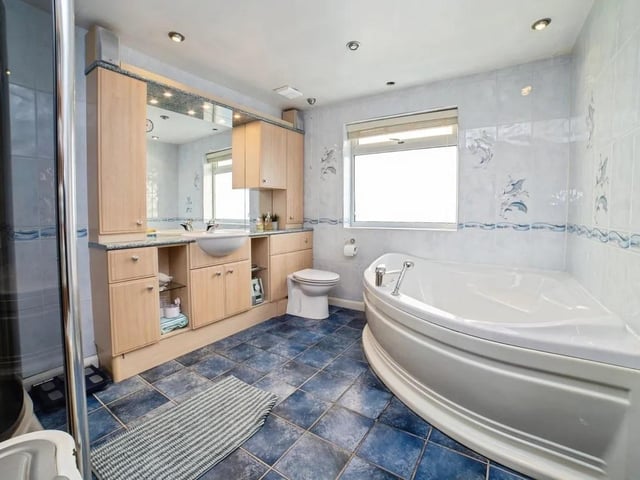 The beautifully designed family bathroom includes a walk-in shower, bathtub, and a vanity with ample storage, offering both style and practicality.