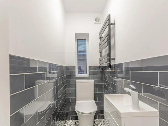 Located on the first floor, the cloakroom consists of ceramic toilet and hand wash basin, double glazed window to side, wall mounted towel radiator, with tiled walls and floors to finish.