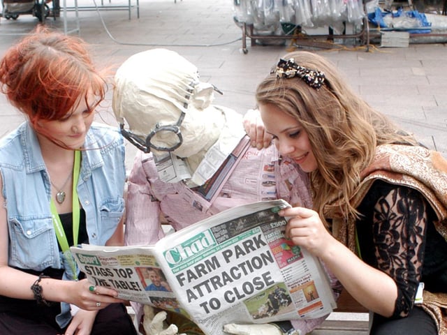 West Notts College students, Francesca Willcock, left, and Sarah Lamb, right, read the Chad along with their latest piece of artwork in Mansfield Market Place. The life size models were part of their art and design foundation course. 2010.
