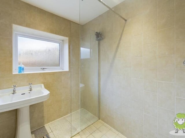 The property includes three bathrooms, including this one downstairs, which features a shower cubicle and wash basin. There is also a separate WC on the ground floor.