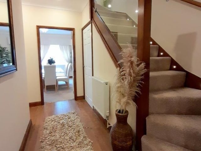 It's time to move up to the first floor now, so we return to the entrance hallway to meet a staircase with plinth lighting. The hallway has a laminate floor and an under-stairs storage space.